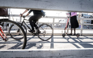 Unga människor som cyklar och åker elsparkcykel på bro i Stockholm.